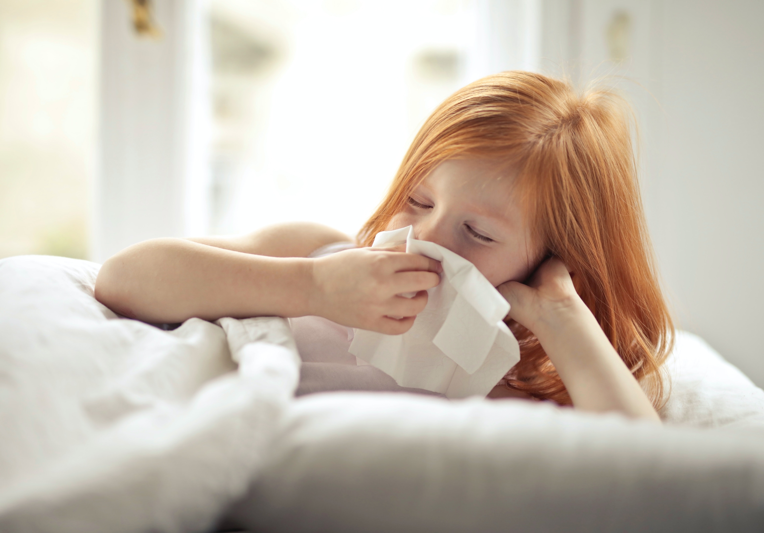 Girl sneezing into tissue