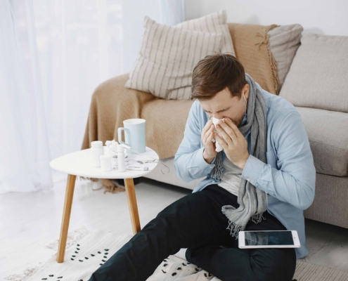 Man sneezing next to his over-the-counter allergy medications