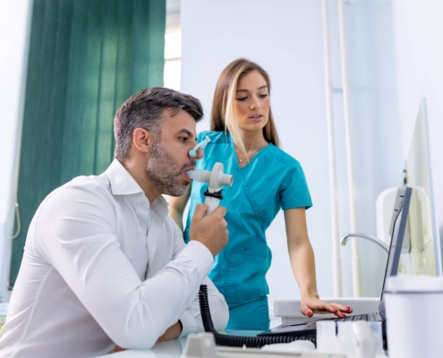 Hombre adulto realizando una prueba de espirometría para evaluar la función pulmonar y diagnosticar asma.