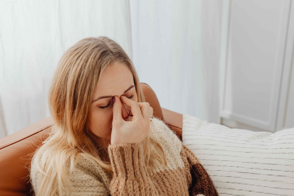 Woman dealing with sinus pressure caused by indoor allergies during winter