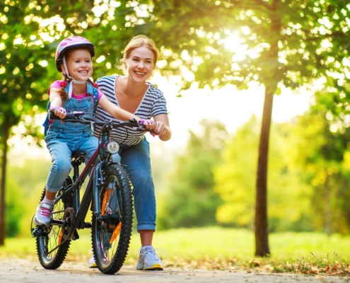 Mamá enseña a su hija a andar en bicicleta mientras viven sin alergias