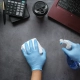 Hands wearing blue latex gloves and using cleaning supplies to clean a desk