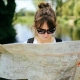 Woman outside wearing sunglasses and reading a map