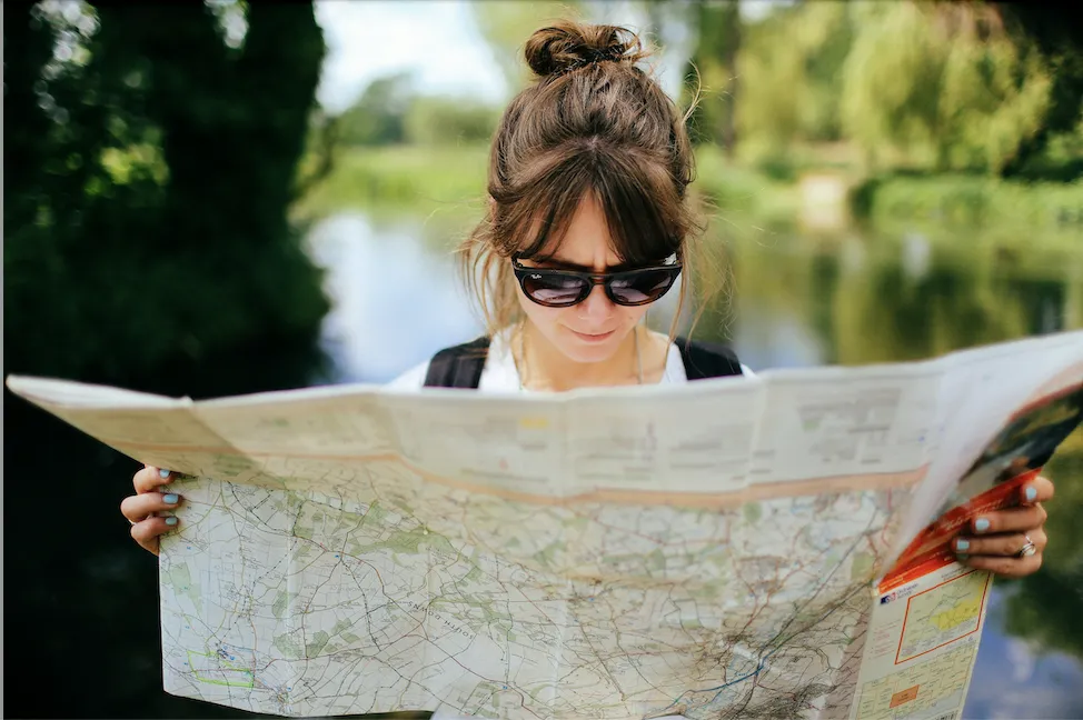 Woman outside wearing sunglasses and reading a map