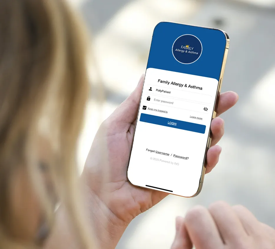 Hand holding a phone with the Family Allergy & Asthma app pulled up