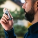 Man managing asthma and allergy symptoms with an inhaler.